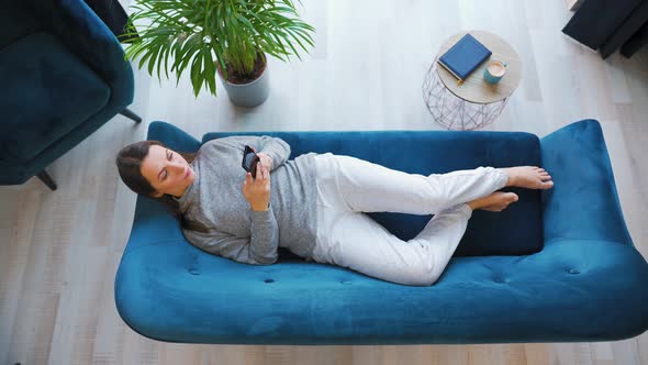 Overhead Shot of Happy Relaxed Woman Holding Smart Phone Using Mobile Apps Watching Funny Video