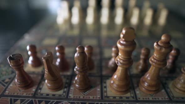 Close up shot of wooden chess pieces ready for chess game on retro chessboard during daytime. Blurre