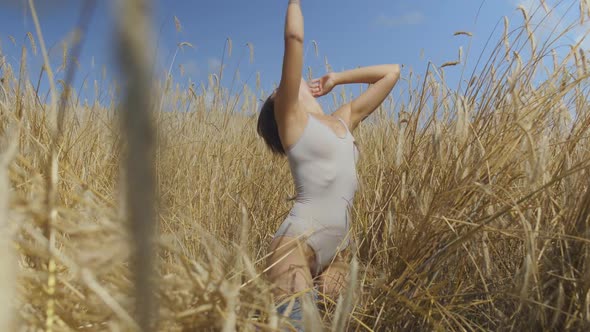 Chic Woman with Short Hair Wearing Bodysuit Relaxing on the Wheat Field