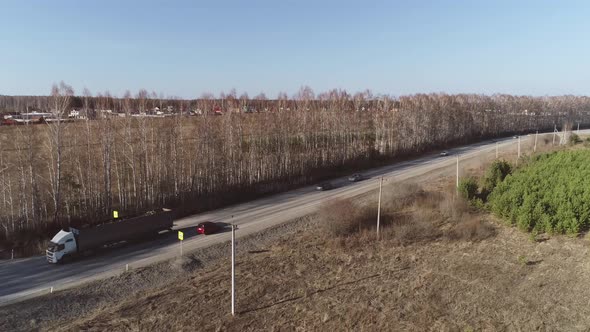 Aerial view of truck and cars are driving along the road near the village 07