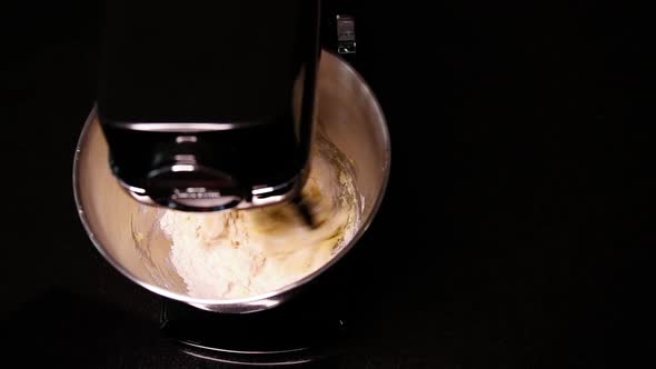 Medium shot of eggs being mixed into white cake batter.