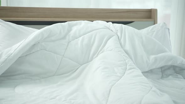 A girl playing with a blanket on the white bed, The cosy at home in the morning of the family