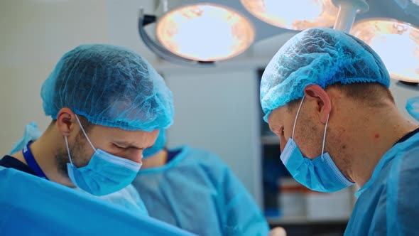 Two doctors and female assistant in surgical uniform