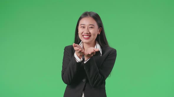 An Asian Business Woman Blowing Kisses And Smiling To Camera In The Green Screen Studio