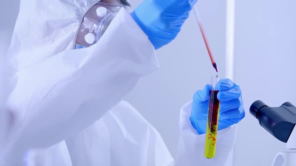 Scientist in PPE suite doing some research checking a liquid in a test tube at laboLabroom01774799 1