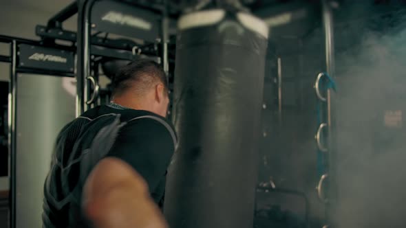 Strong Man Hitting Punching Bag Indoor of Modern Gym