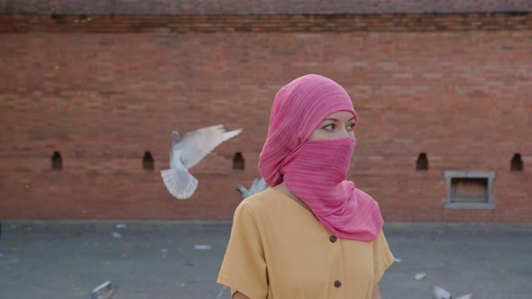 Attractive Muslim Woman with Natural Make Up Wearing Pink Hijab Scarf Looks at Camera