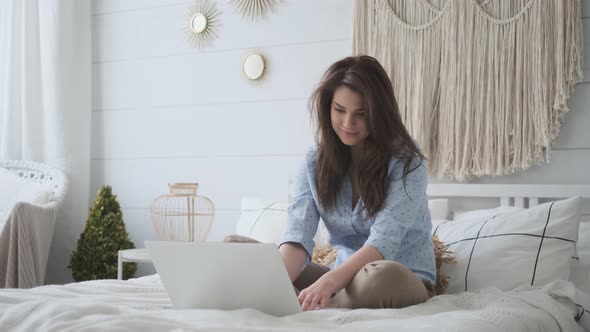 Portrait of an Attractive Young Woman in Casual Dress at Home. Young Girl Working on a Laptop While
