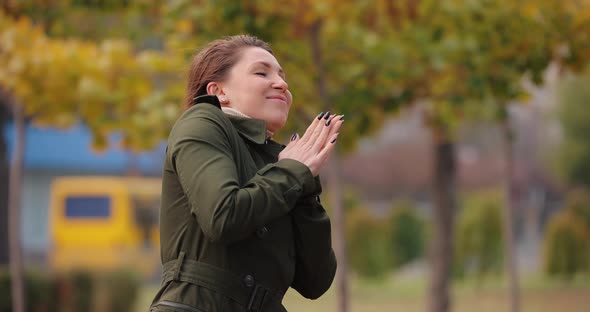 Woman Warming Her Cold Hands at the Autumn Day