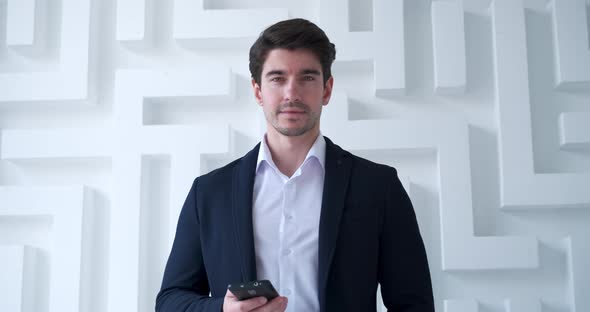 Portrait of Young Confident Business Man Using Smartphone in Modern Office