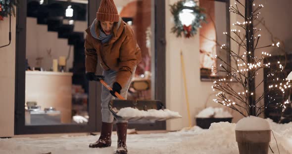 Woman Cleaning Snowy Backyard of Her House