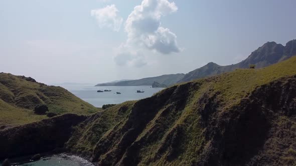 Aerial of dense green mountains at the coastline of beautiful blue ocean. Indonesien, Labuan Bajo, K