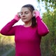 Young Active Sports Girl in Workout Clothes Puts on Wireless Headphones to Start Running in the City - VideoHive Item for Sale