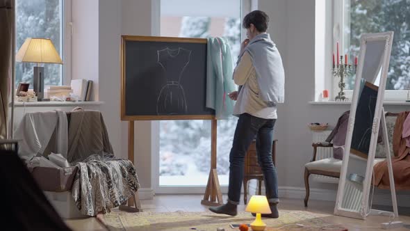 Wide Shot of Talented Fashion Designer Drawing Dress Sketch on Blackboard with Chalk