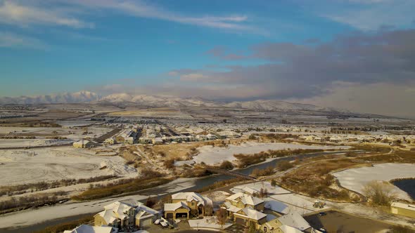Flying towards a suburban, urban area on a snowy day and a community beneath the mountains - aerial