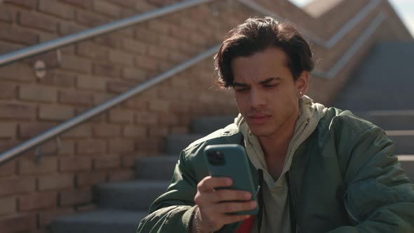 Stylish Guy with Serious Face Using Smartphone Outdoors