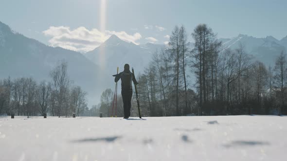 Man Walking Through Snow And Holding Skis