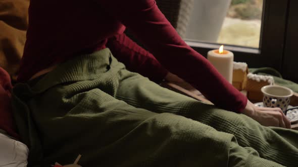 Woman drinking a coffee in a bed and reading a book.