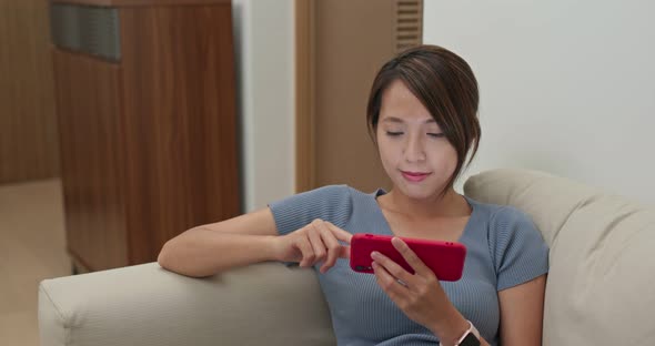 Woman look at mobile phone and sit on sofa at home