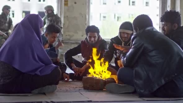 Refugees Sitting by Fire in Abandoned Building