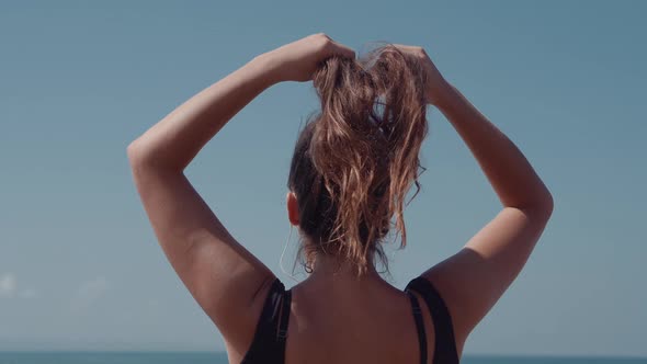 Unrecognizable Female is Tying Ponytail Enjoying a Sea View