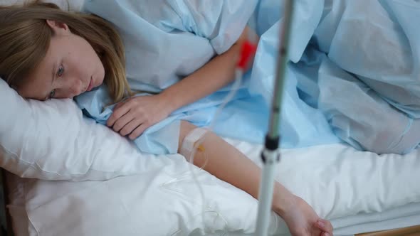 High Angle View Portrait of Depressed Teenage Girl with Eye Dropper Lying in Bed in Hospital Ward