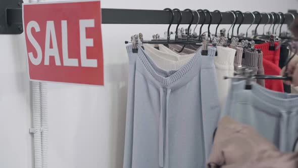 Unrecognizable Woman Taking Hangers From Sale Rack Leaving