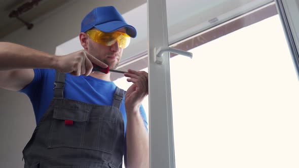 Man in Goggles Fixes Flat Window Handle with Screwdriver