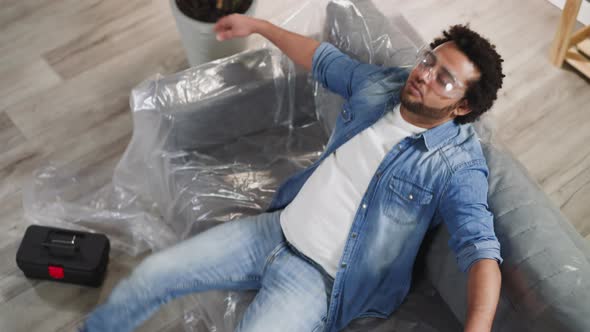 Exhausted Black Man Falls Down and Takes Off Glasses on Sofa