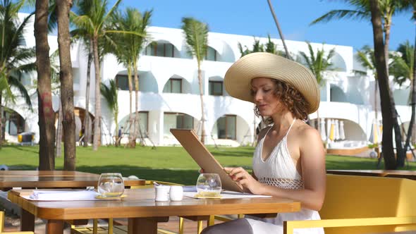 Beautiful Young Woman In Hat Reading Menu In Beach Restaurant