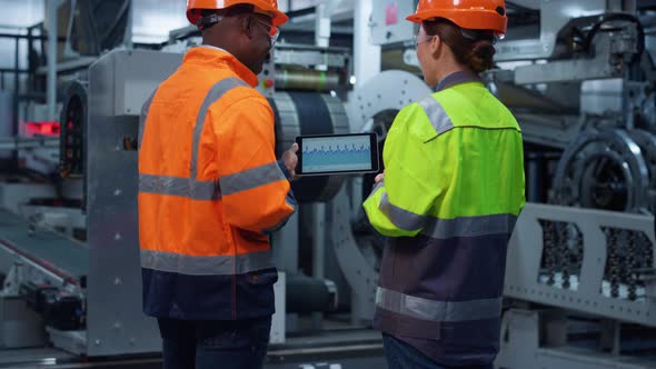 Focused Partners Discussing Charts on Modern Tablet Computer at Huge Factory