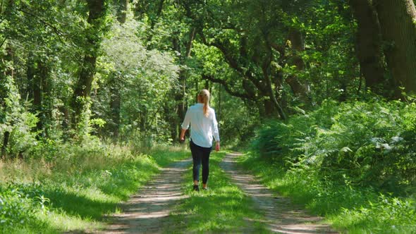 Blonde woman walking through lush woods, SLOWMO ZOOM IN