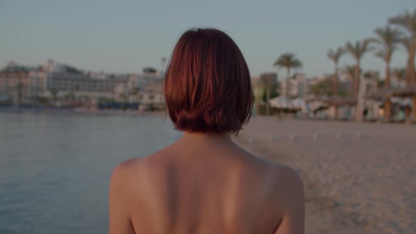 30s Woman in Swimsuit Walking on Sea Shore and Watching Beautiful Sunrise Over the Sea