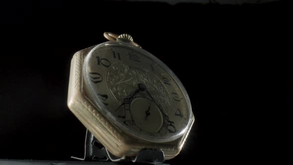 Gold Antique Pocket Watch on a Stand Rotating on a Black Isolated Background