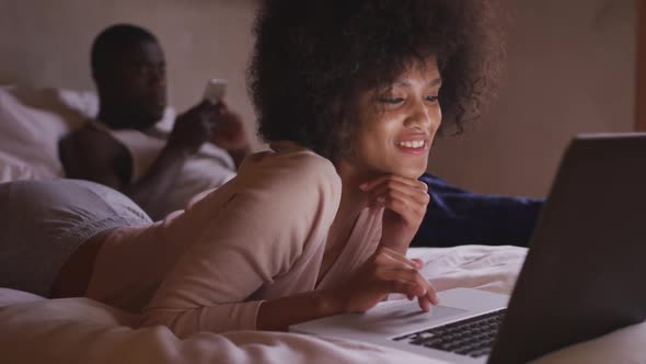 Couple on smartphone or computer in bedroom