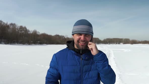 Smiling Thirty-Year-Old Man Is Taking By The Phone Near The Forest In Winter