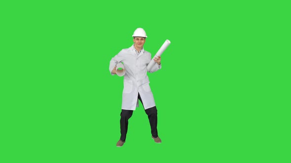 Happy Young Engineer Dances with Blueprints in a Funny Way on a Green Screen, Chroma Key