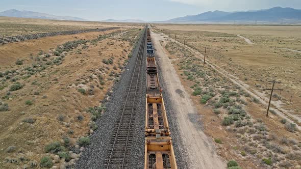 Flying over train tracks with empty cars in the Utah desert