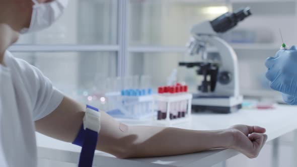 Unrecognizable Doctor Taking Blood Sample from Sick Patient