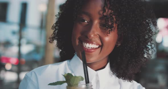 Woman smiles while holding glass of cold drink