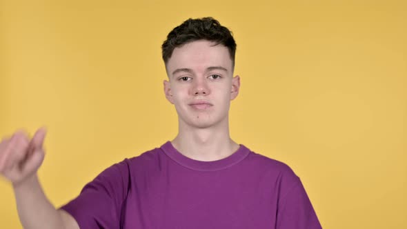 Thumbs Down By Young Man, Yellow Background