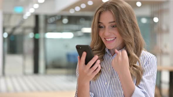 Portrait of Excited Businesswoman Celebrating Success on Smartphone 