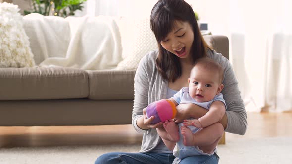 Happy Mother with Baby and Ball Playing at Home