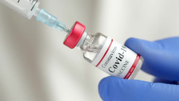 Doctor Holding Coronavirus Vaccine and Syringe to Prevent COVID19 Infection