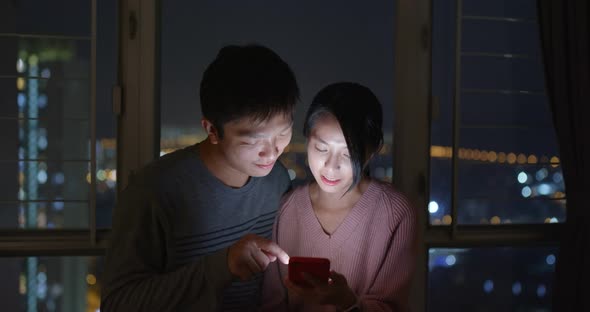 Couple use of mobile phone together at home