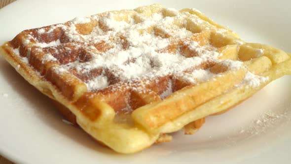 Preparation of waffles. Waffles are sprinkled with powdered sugar.