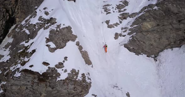 Aerial drone view of a mountain climber climbing up with crampons in the snow.