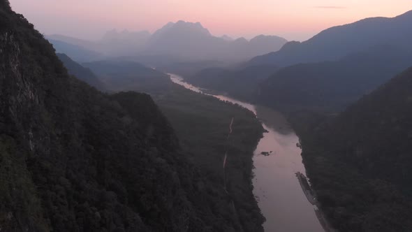 Aerial: drone flying over Nam Ou River valley canyon Nong Khiaw Muang Ngoi Laos, sunset dramatic sky