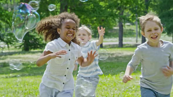 Funny Kids Running and Playing with Bubbles at Sunny Day alt