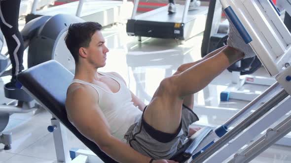 Handsome Young Ripped Male Athlete Exercising on Leg Press Machine